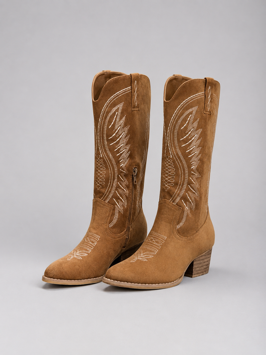 Pair of tall brown cowboy boots with pointed toes, decorative Western stitching, side pulls, and stacked block heels.