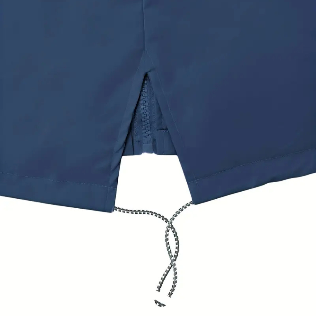 Model wearing a hooded long rain coat with a front zip, drawstring waist, and front pockets on a wet city street._12