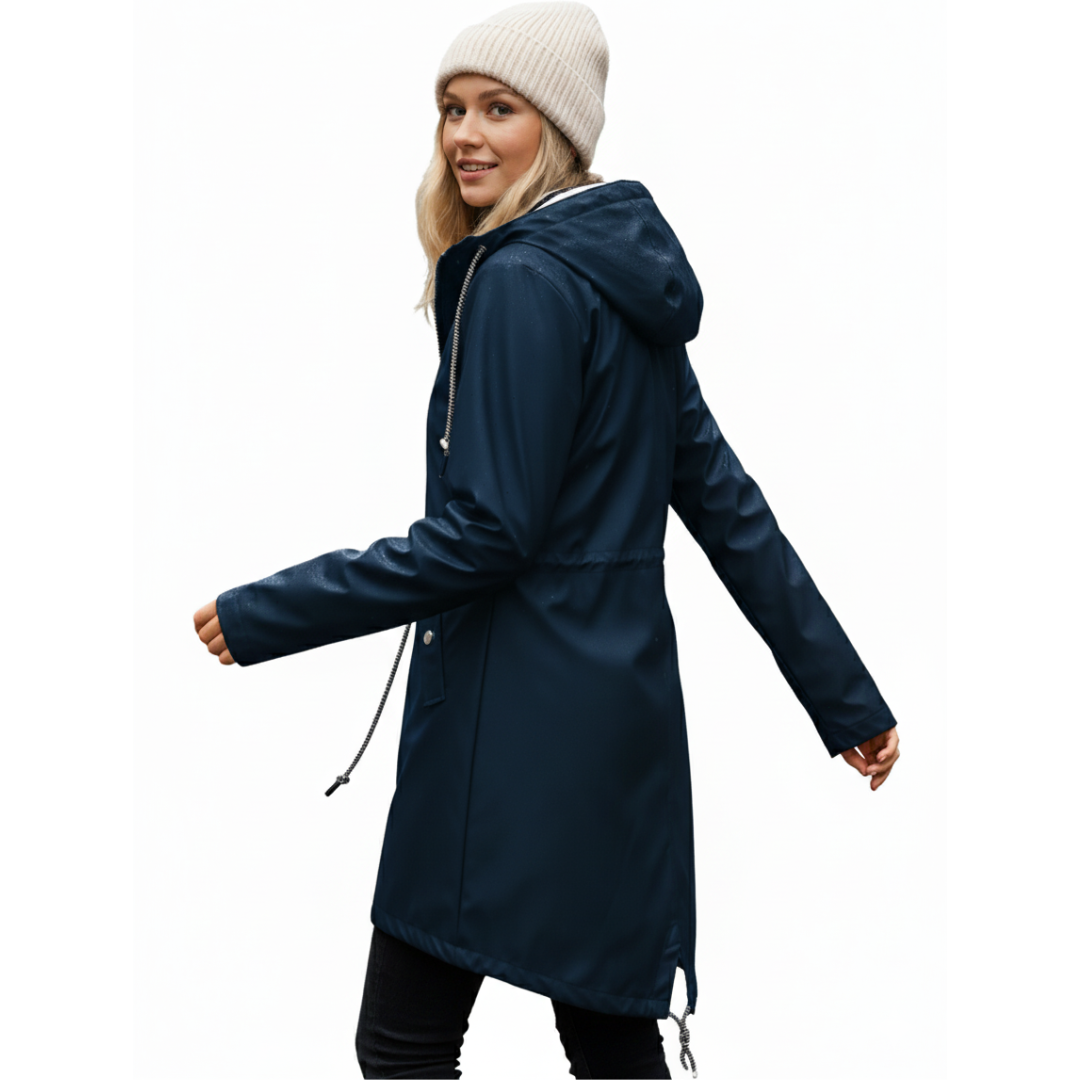 Model wearing a hooded long rain coat with a front zip, drawstring waist, and front pockets on a wet city street._14