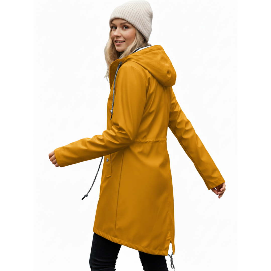 Model wearing a hooded long rain coat with a front zip, drawstring waist, and front pockets on a wet city street._16