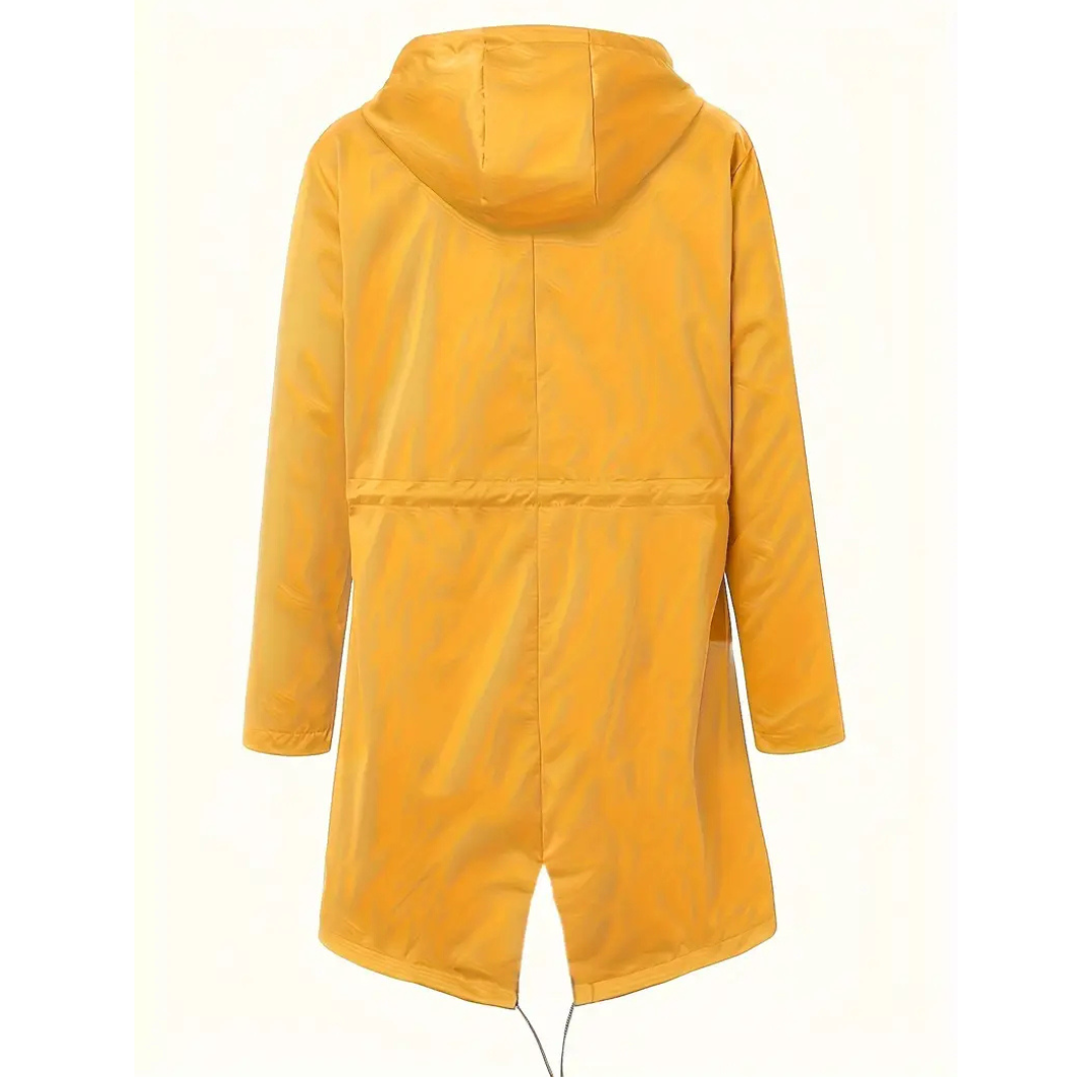 Model wearing a hooded long rain coat with a front zip, drawstring waist, and front pockets on a wet city street._17