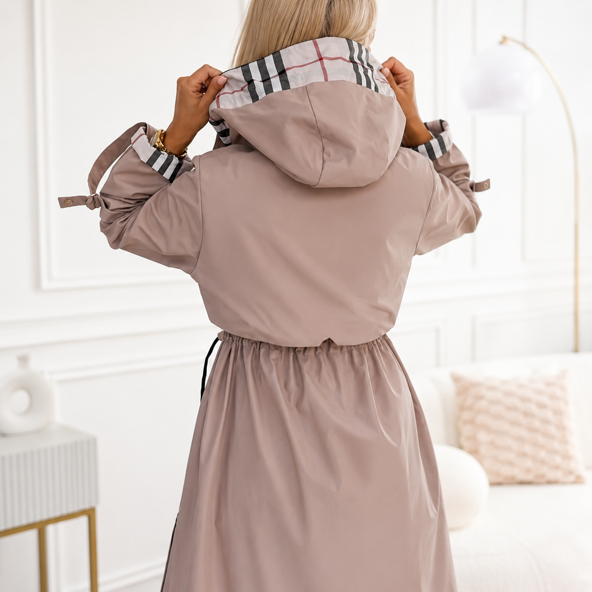 A woman wears a hooded zip coat with an adjustable drawstring waist and front pockets on a city street._10