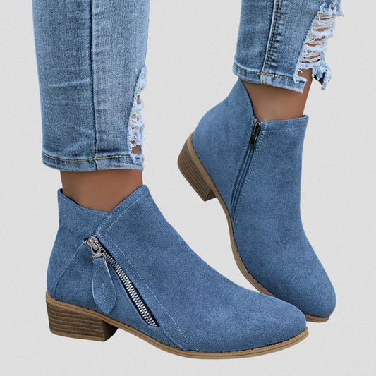Blue ankle boots with side zippers and low stacked block heels shown worn with distressed jeans, including a close view of the zipper detailing.
