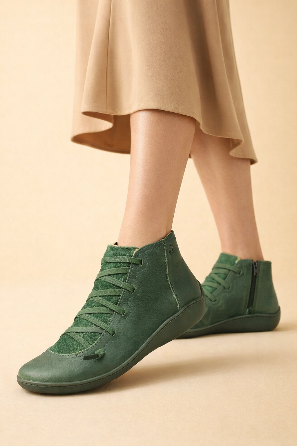 Green women's lace-up ankle boots paired with a flowing tan skirt, with one boot shown in front and the other turned to reveal its side zip.