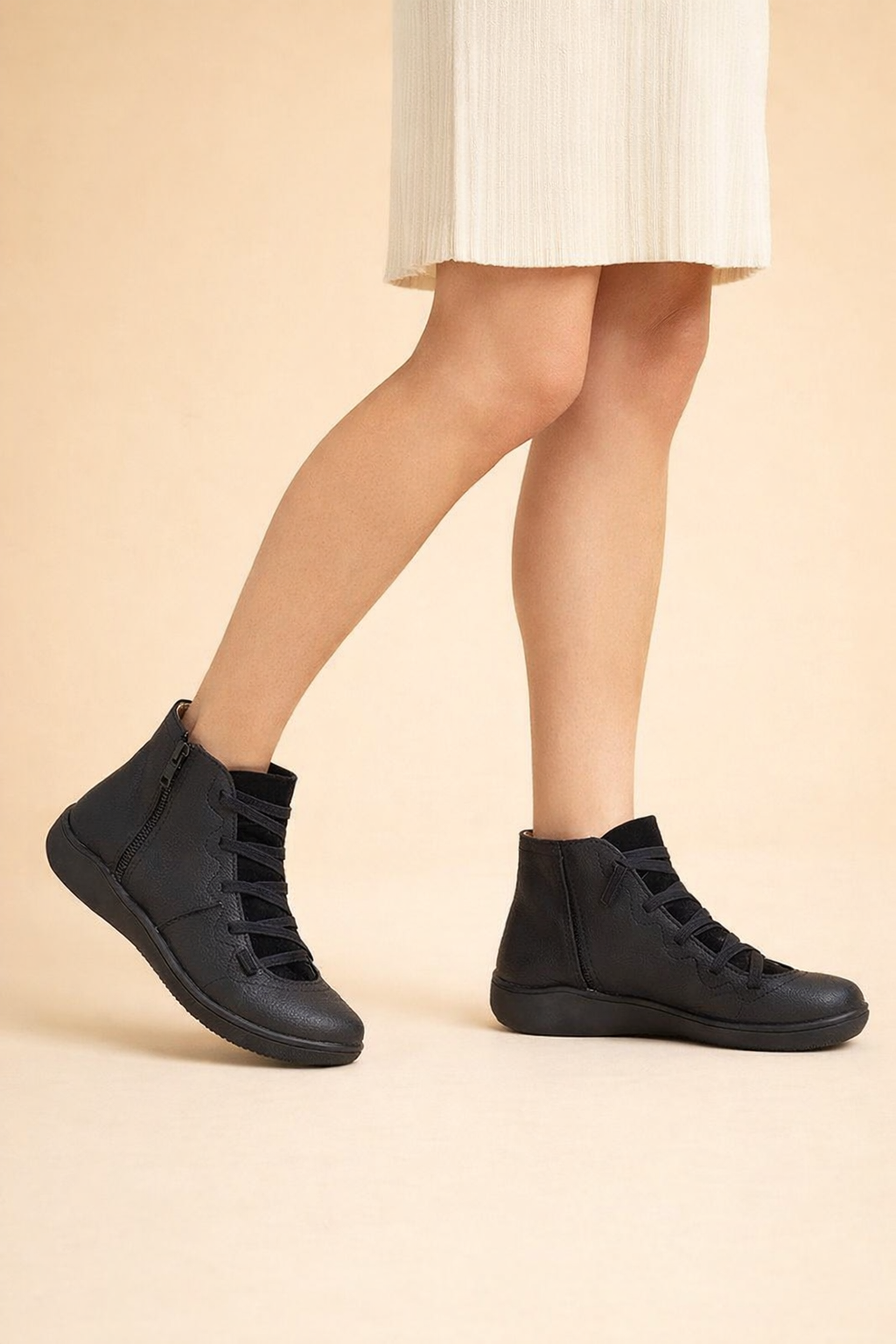 Black women's lace-up ankle boots worn with a light skirt, shown in a side-facing walking stance.