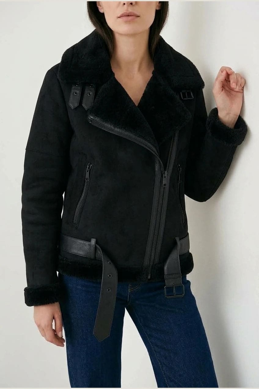 Woman wearing a hip length aviator jacket with a wide fleece collar, asymmetric zip, buckled waist tabs and side pockets, with straight jeans and ankle boots._2
