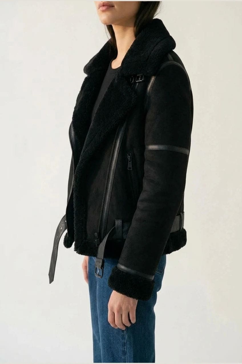Woman wearing a hip length aviator jacket with a wide fleece collar, asymmetric zip, buckled waist tabs and side pockets, with straight jeans and ankle boots._3