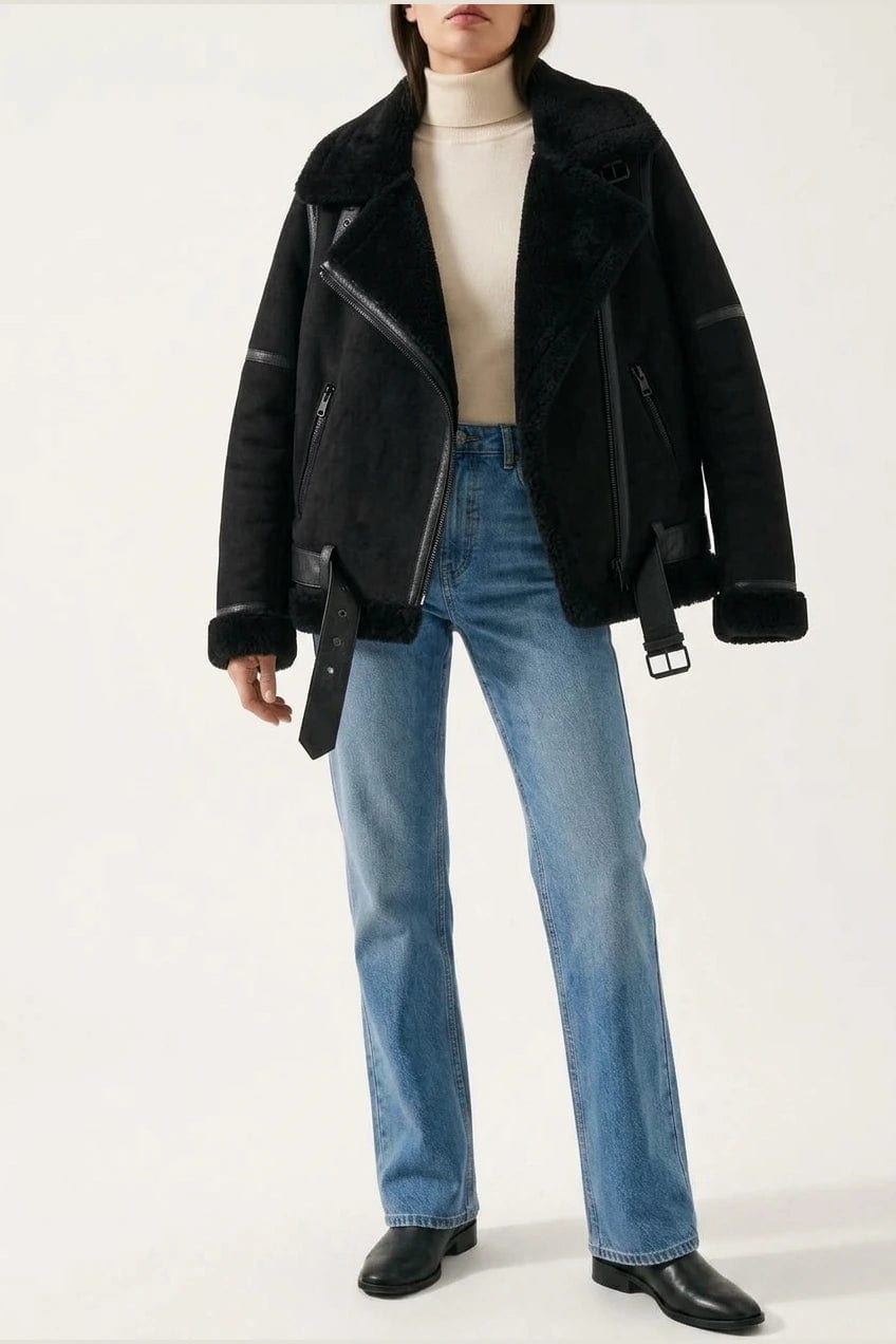 Woman wearing a hip length aviator jacket with a wide fleece collar, asymmetric zip, buckled waist tabs and side pockets, with straight jeans and ankle boots._4