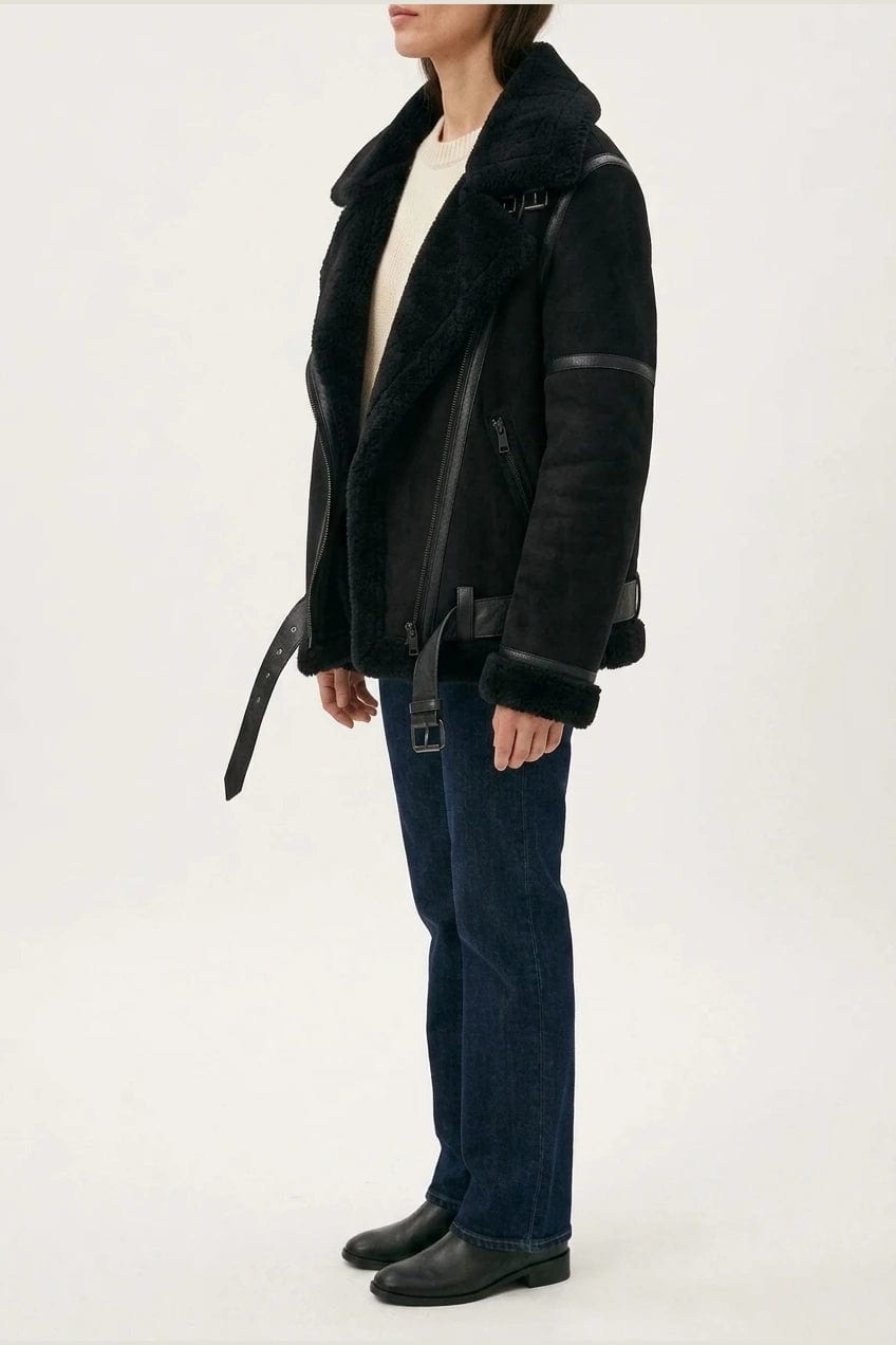 Woman wearing a hip length aviator jacket with a wide fleece collar, asymmetric zip, buckled waist tabs and side pockets, with straight jeans and ankle boots._5